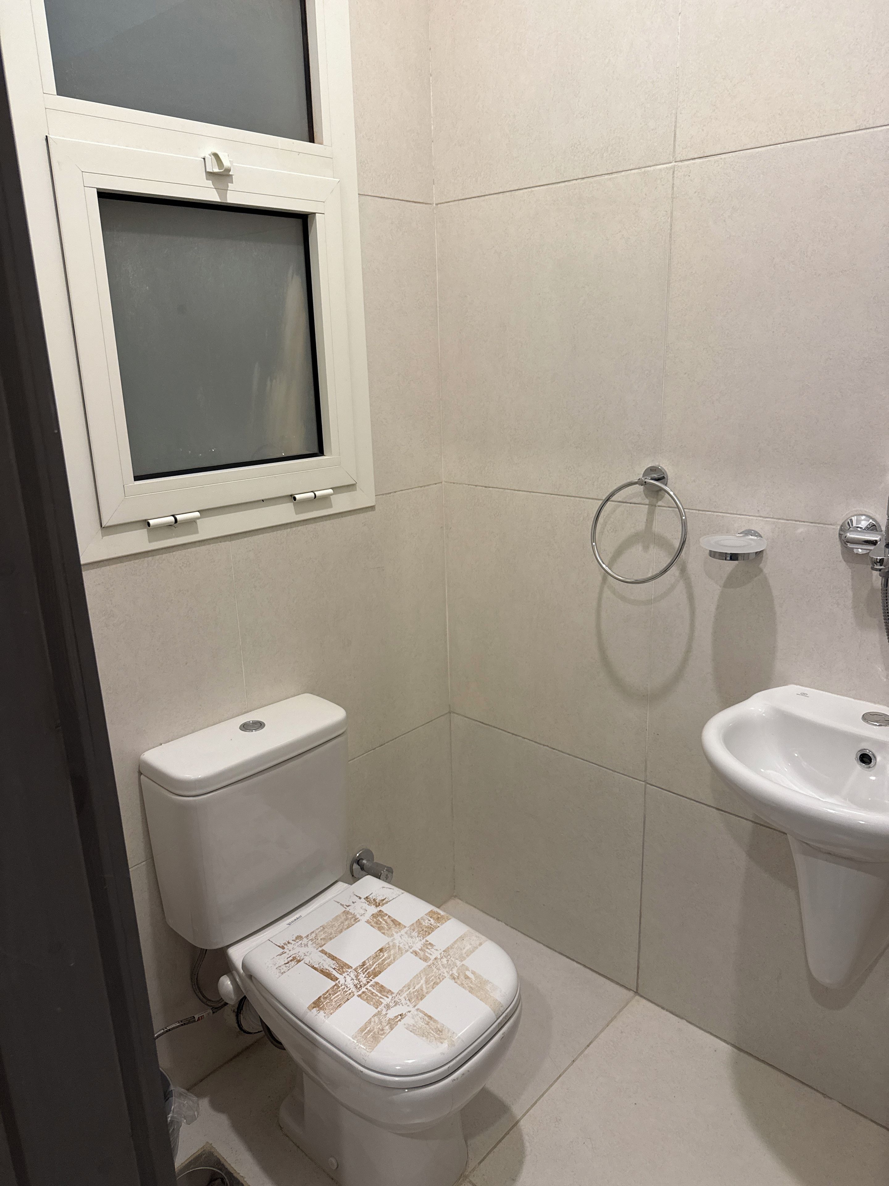 Ein kleines, sauberes Badezimmer mit Toilette, Waschbecken und Fenster.