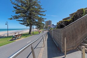 A coastal walkway with a bench, a metal railing, and a view of the beach. - Glee Tides By the Beach Indoor outdoor Lifestyle (Glenelg East)