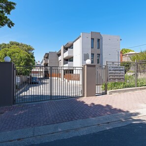 Edifici residencial amb tancat de disseny modern, que disposa d'una zona d'aparcament i una bústia.