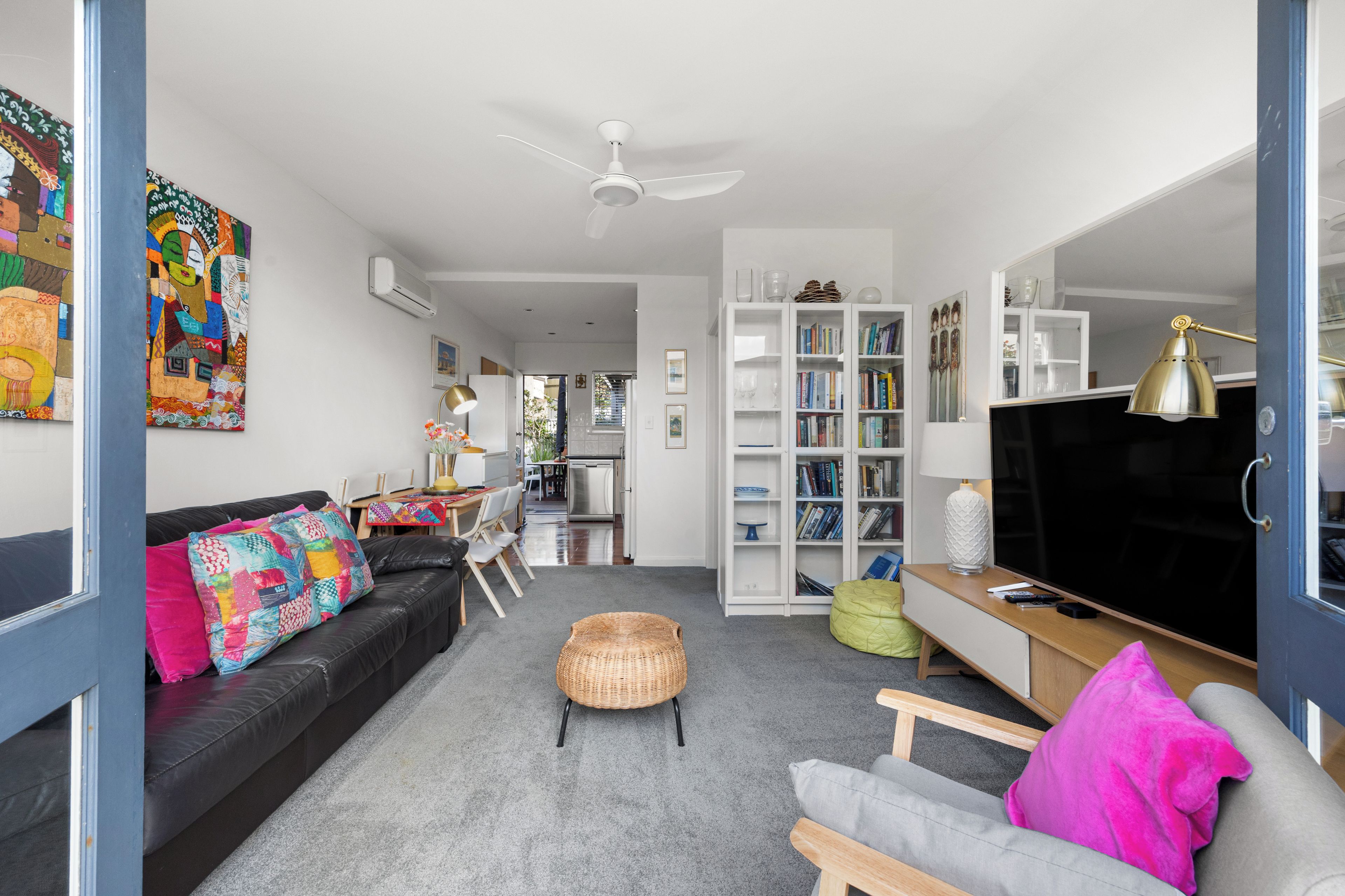 A modern living room with a sofa, a coffee table, a television, and a bookshelf.