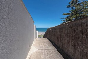 A concrete pathway leading to a beach with a clear blue sky. - Glee Tides By the Beach Indoor outdoor Lifestyle (Glenelg East)