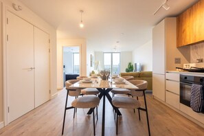 A modern kitchen with a dining area, wooden cabinets, and a view to the living room. - Birmingham City Retreat No 154 (Birmingham)