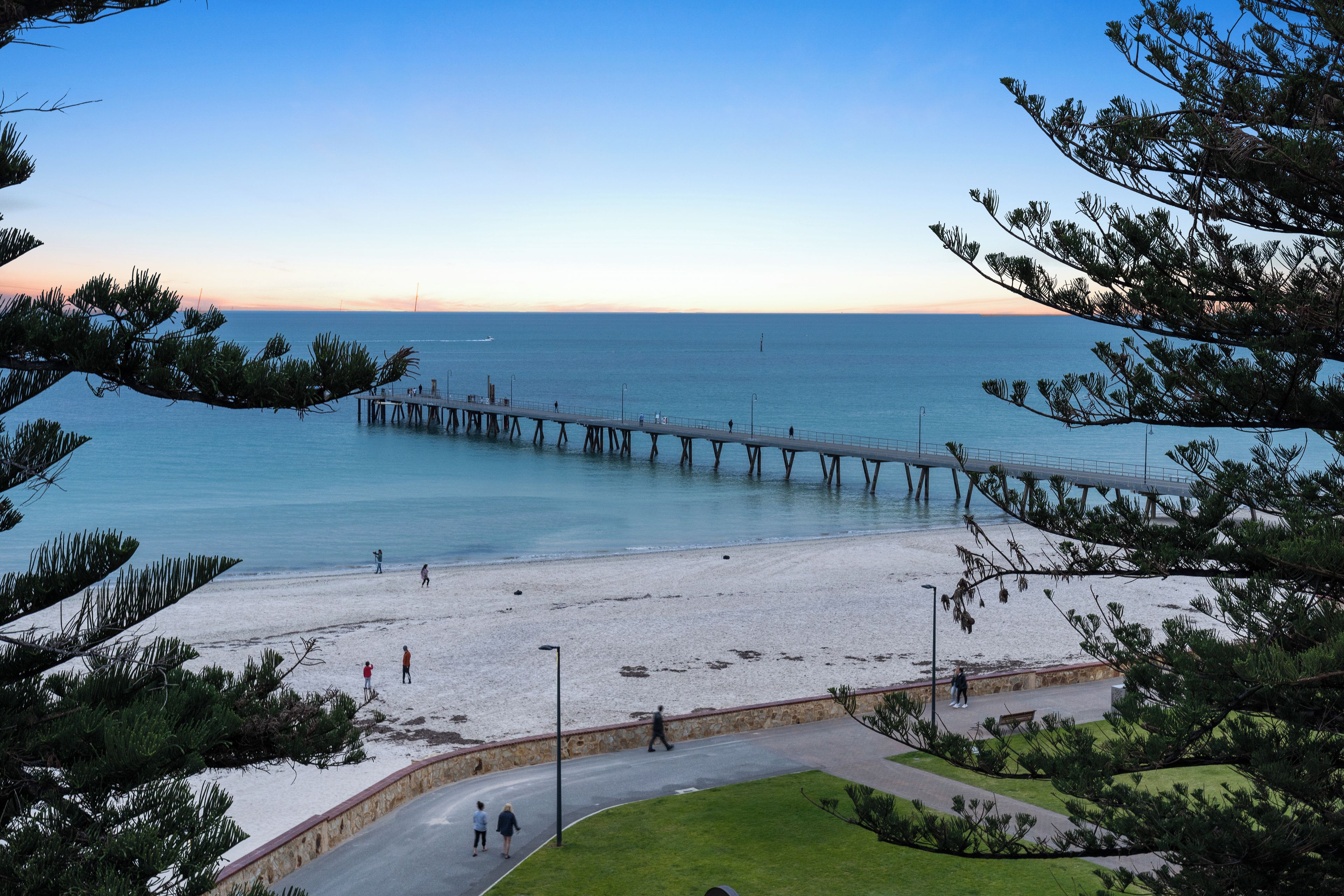 A pier extending into calm waters with a clear sky above.