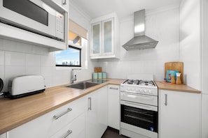 Eine moderne Küche mit weißen Schränken, einem eingebauten Herd, einer Mikrowelle und einem Toaster.