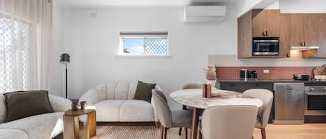 Un espacio de estar moderno con sofá, mesa de comedor, sillas y una cocina equipada.