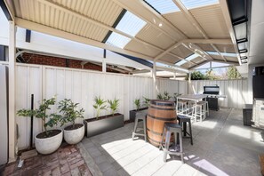 Eine Außenpatio mit Grill, Sitzgelegenheiten und Topfpflanzen.