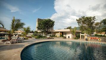 Zona de piscina con sillas de descanso y un edificio al fondo.