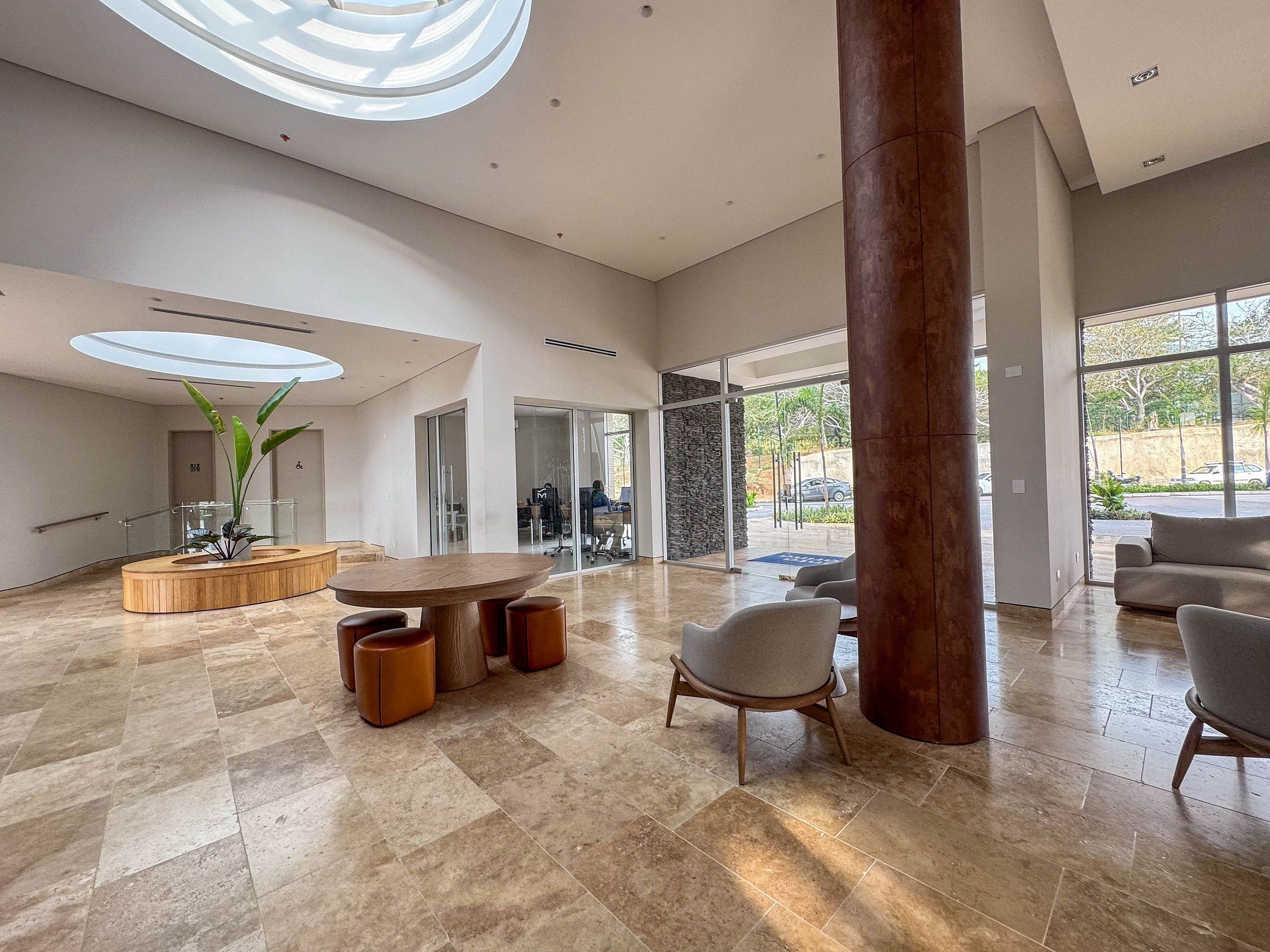A spacious lobby with a round wooden table, seating, and a large pillar.