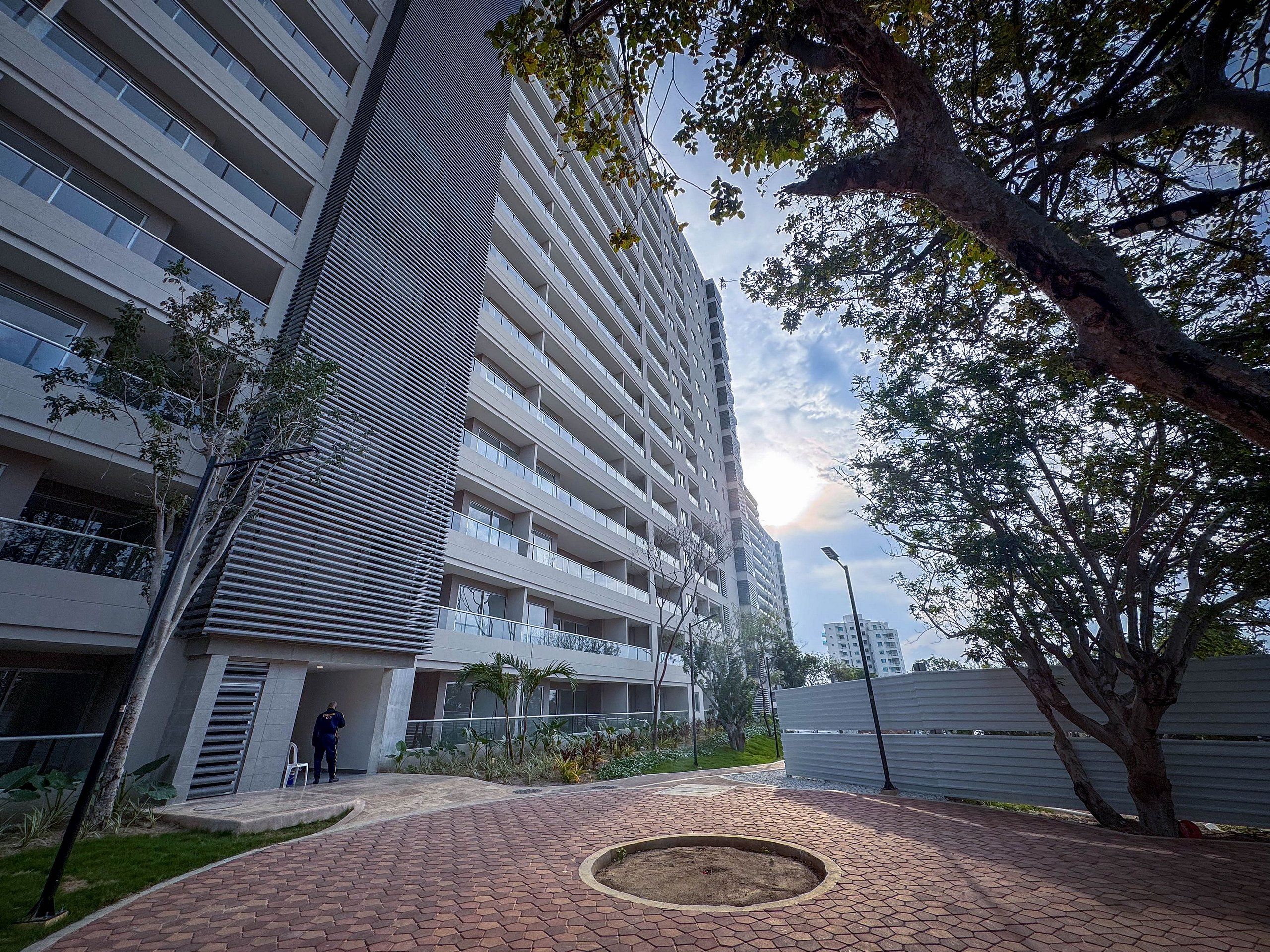 A multi-story residential building with a modern architectural design, featuring balconies and a paved courtyard.