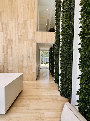 Un interior modern amb sòl de fusta, una taula de recepció i una paret vertical amb jardí.