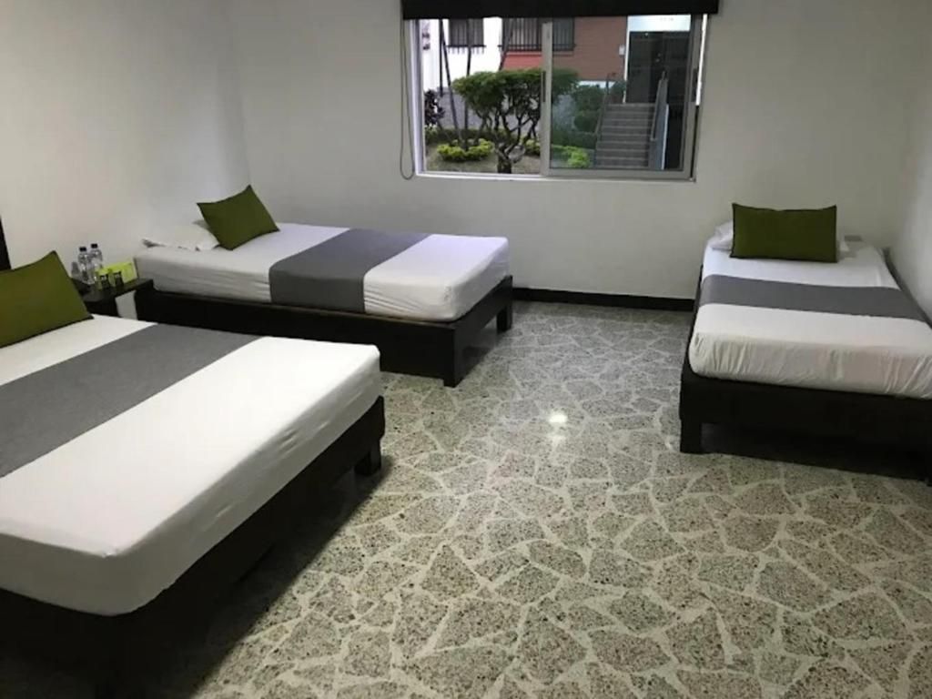 Habitación de hotel con dos camas, una ventana con vistas al exterior y piso de baldosas.