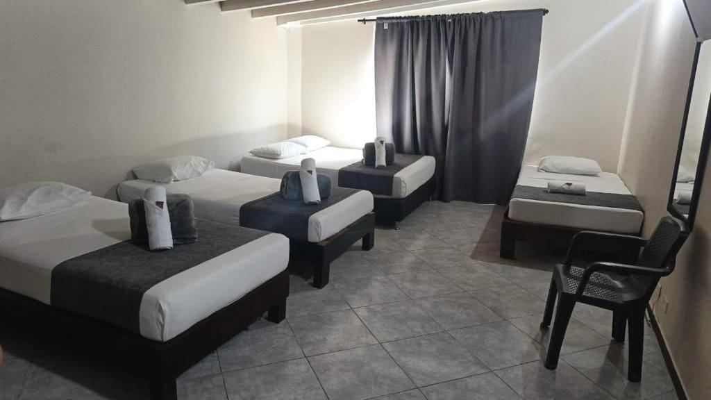 Habitación de hotel con tres camas, un escritorio y una silla.