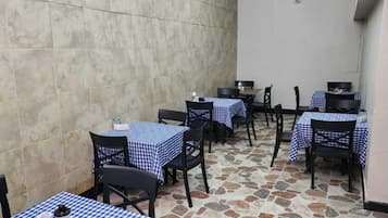 A restaurant with checkered tablecloths, black chairs, and a stone tile floor.