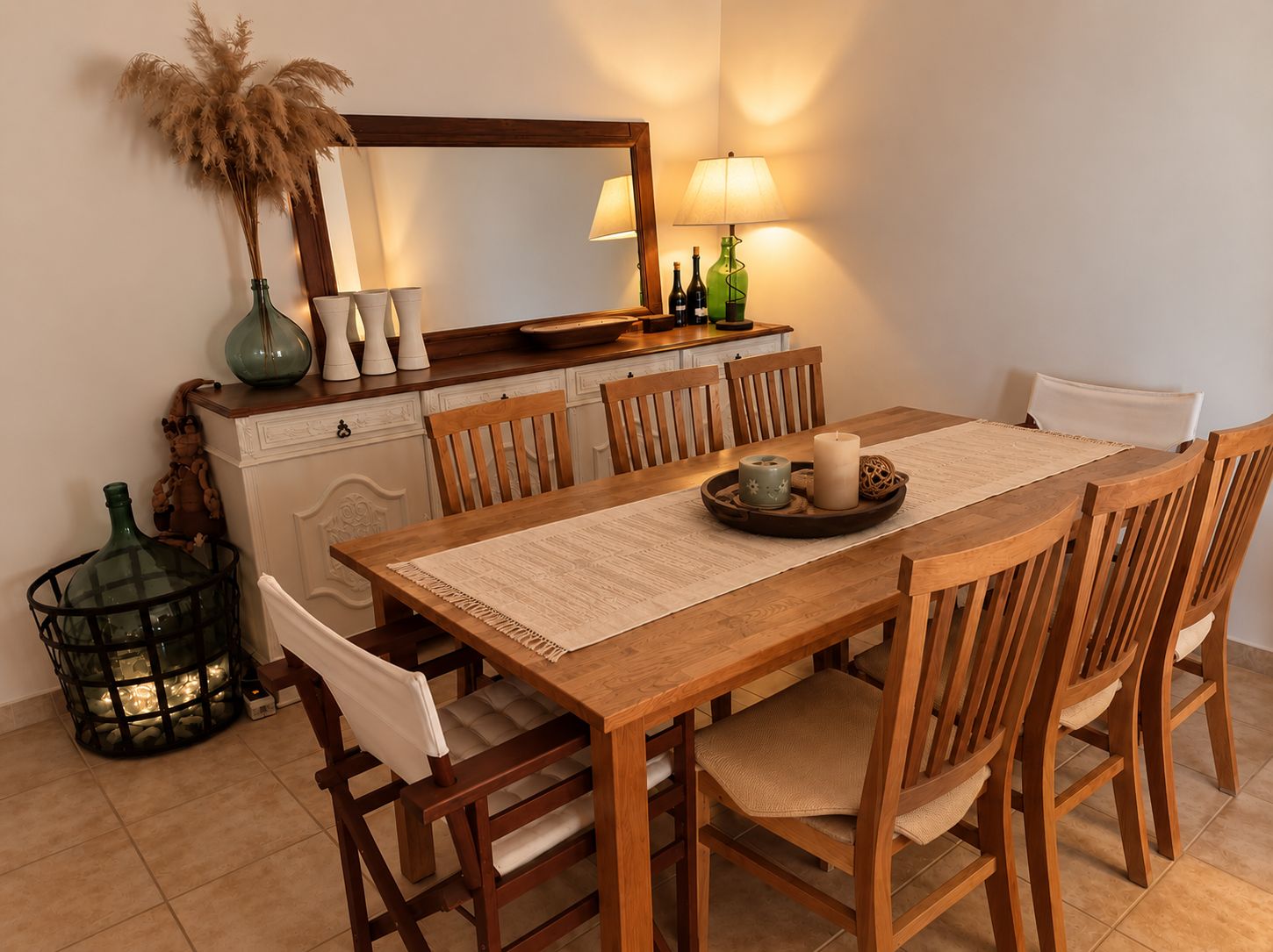 A dining area with a wooden table, chairs, a mirror, and a lamp.