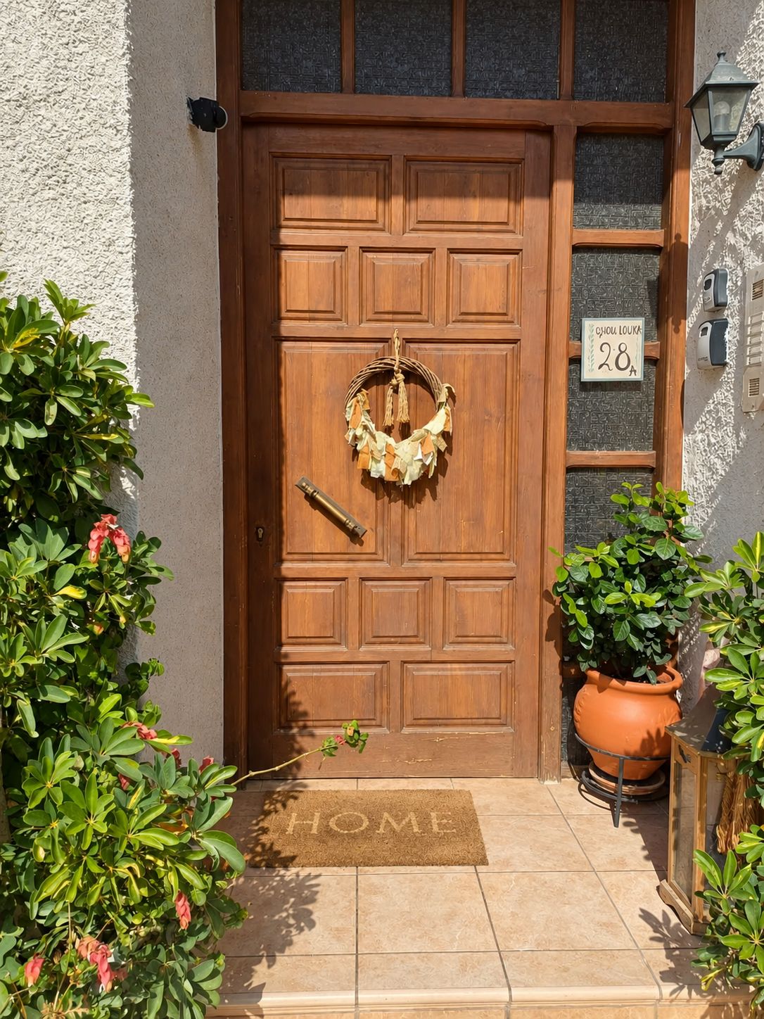 A wooden door with a doormat, a number plaque, and a potted plant.