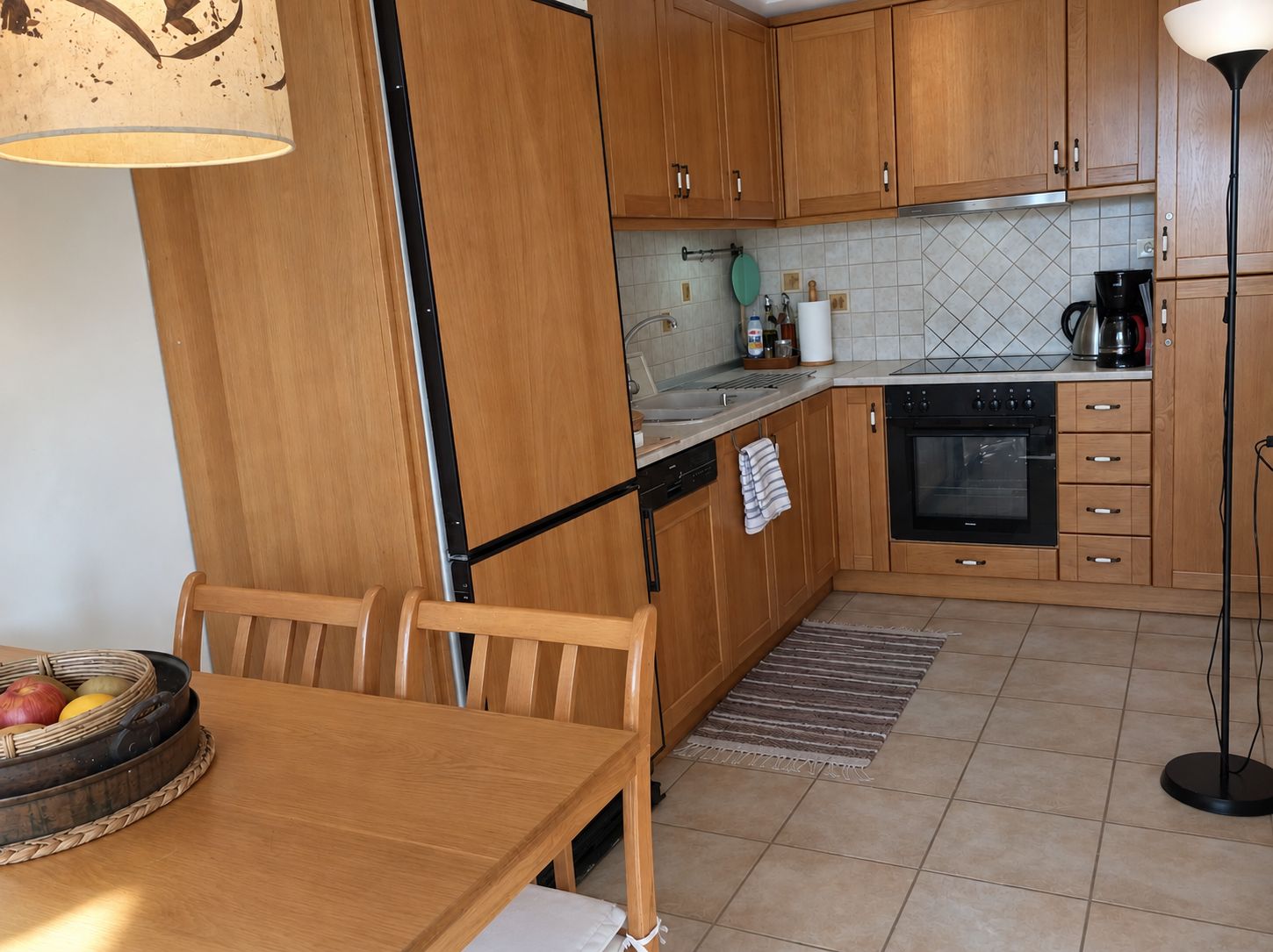 A compact kitchen with wooden cabinets, a built-in oven, and a dining area with a table and chairs.