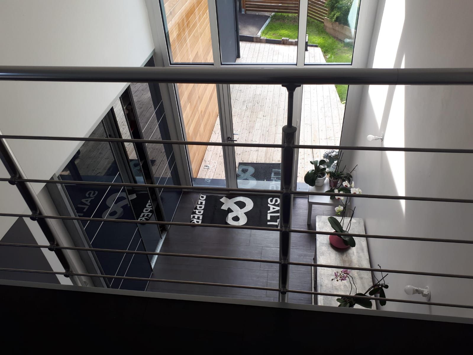 A view from a balcony with a metal railing, a wooden deck outside, and a door marked '8 SALT'.