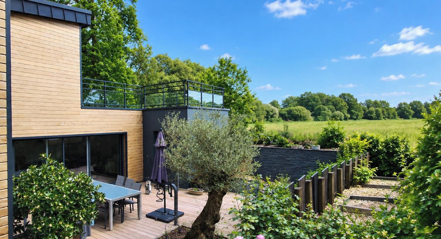 A modern house with a deck, outdoor furniture, and a garden.