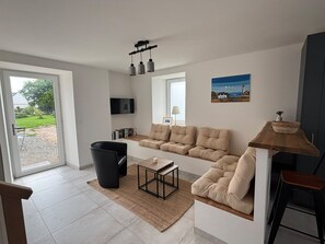 A modern living room with a sofa, a coffee table, and a TV mounted on the wall.