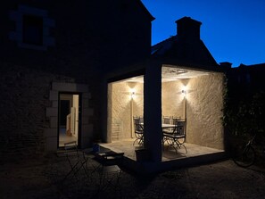 A stone building with a covered patio area featuring outdoor seating. - "Ti Ar Mor" vacation rental by the sea, near Paimpol. (Plouézec)