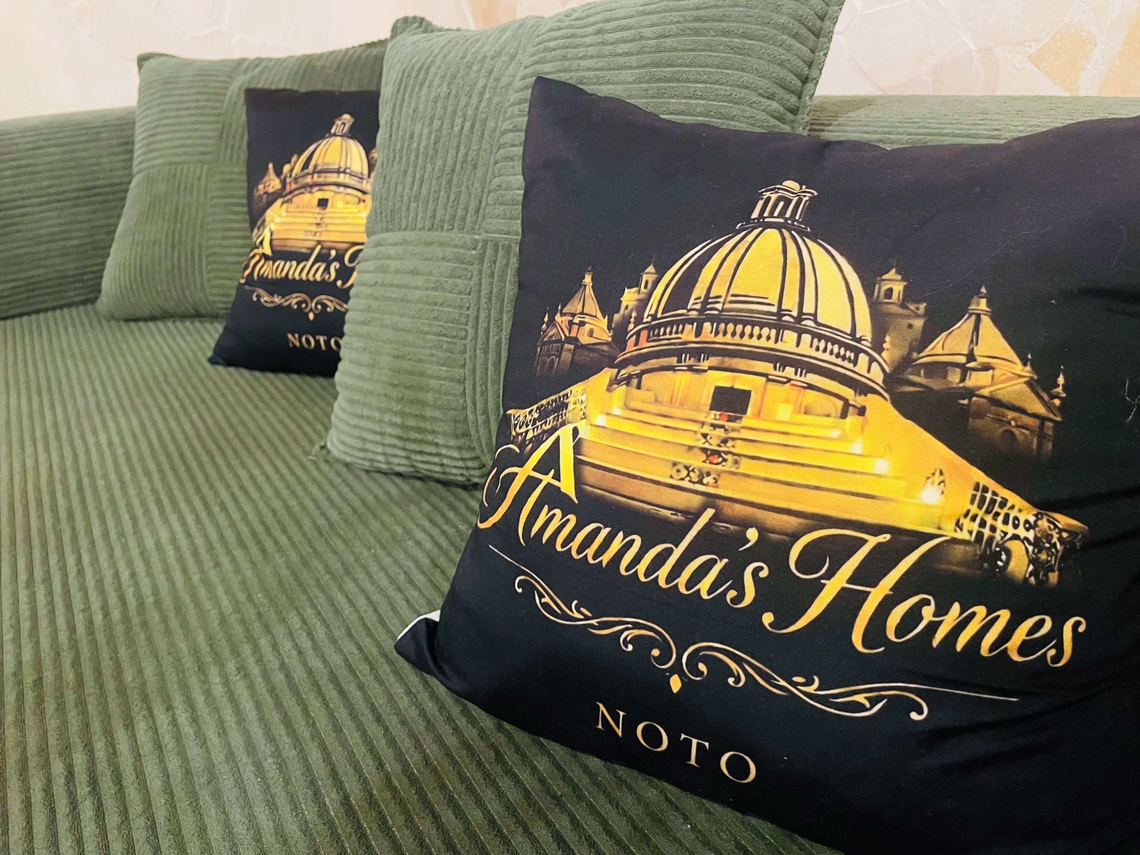 A bed with green bedding and pillows featuring a building illustration and text.