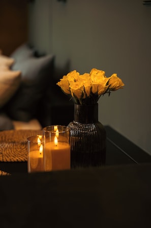 A dark room with a vase of yellow flowers and two lit candles on a table. - Intimate cozy cabin with hot tub in Apuseni Mountains (Mătișești)