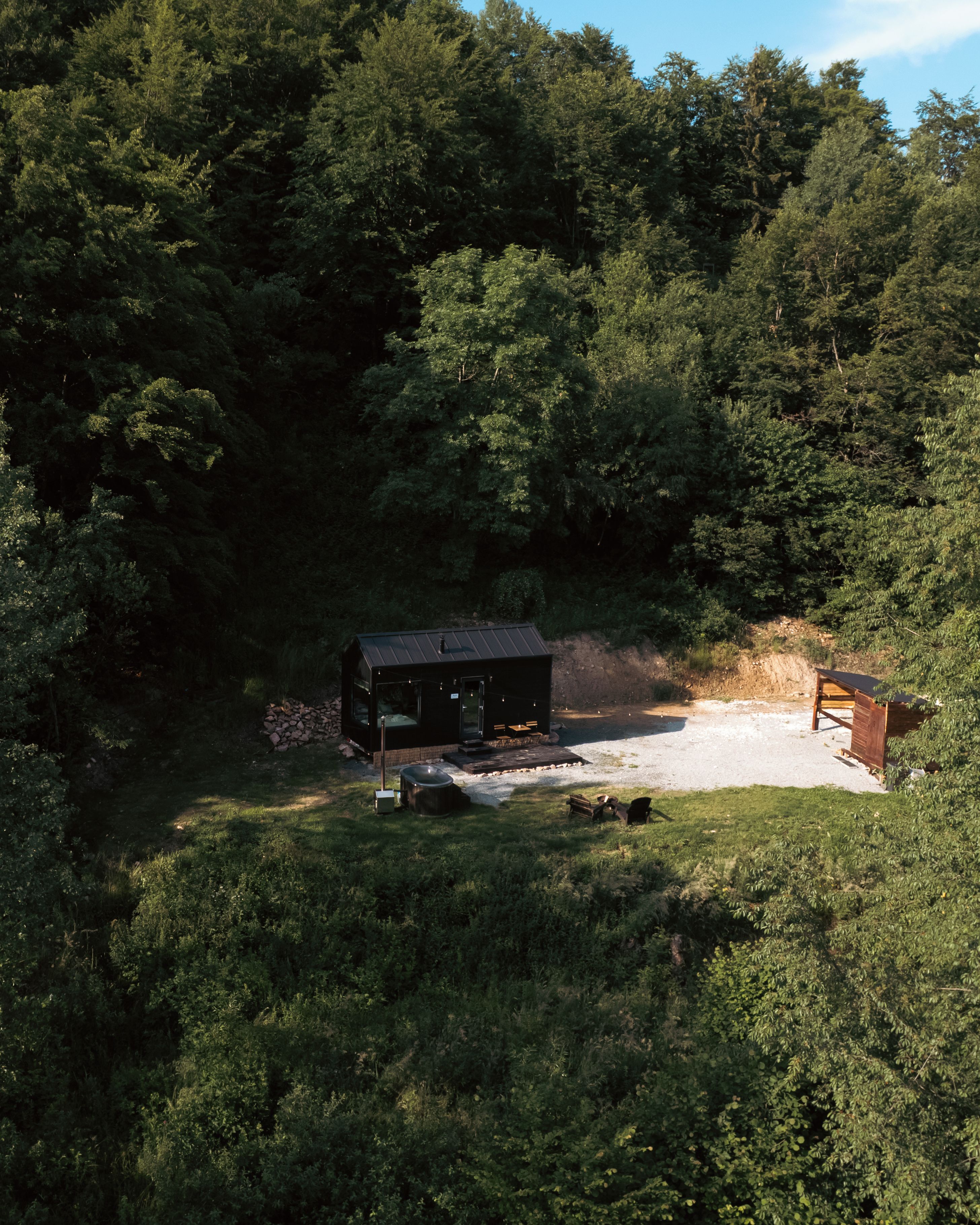 A cabin surrounded by dense forest, with a gravel path leading to it.