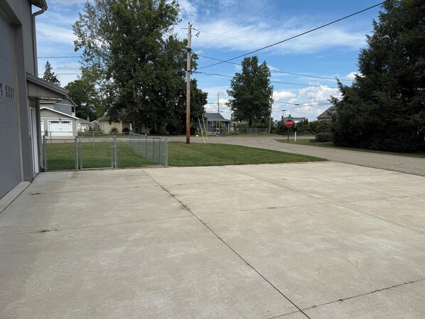 A residential driveway with a garage, a stop sign, and a chain-link fence.
