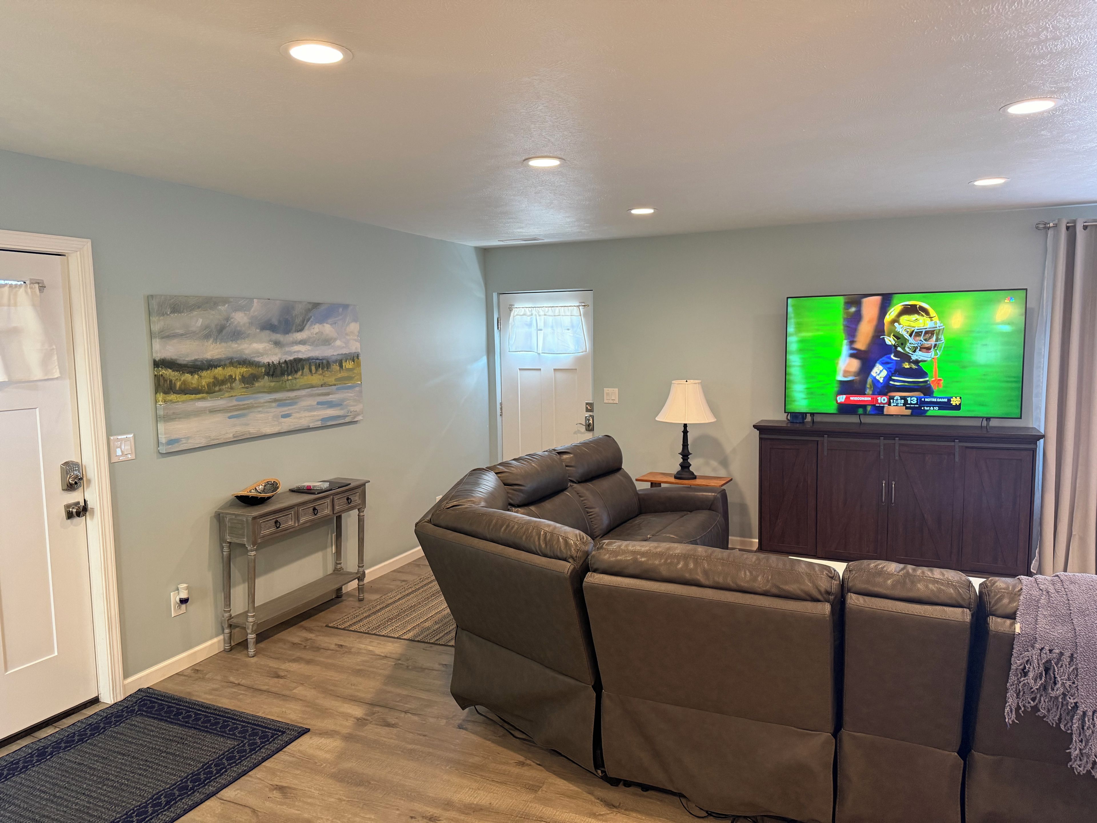 Sala de estar com sofá, televisão, quadro e abajur.