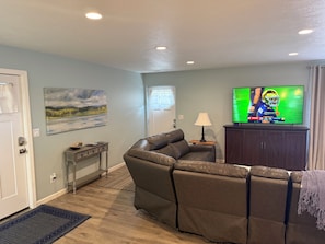 A living room with a sofa, a television, a painting, and a lamp.