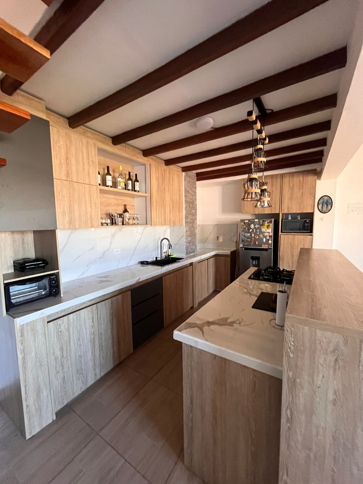 A modern kitchen with wooden cabinets, a marble countertop, and a built-in oven.