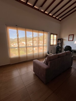 A living room with a large window, a sofa, and a fan.