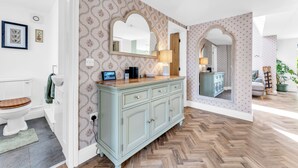 A bathroom with a wooden toilet, a light blue vanity with a mirror, and a herringbone wood floor. - 31 Old Chester Road (Helsby)
