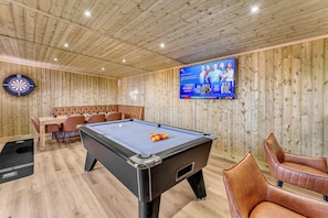 A billiards table with a pool cue, a dartboard, and a television screen displaying sports content. - 31 Old Chester Road (Helsby)