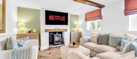 A cozy living room with a fireplace, a television mounted on the wall, and a comfortable sofa.