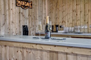 Uma área de bar com painel de madeira, uma garrafa de champanhe e dois copos em um balcão.