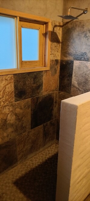 A bathroom with stone tiles, a wooden window, and a shower. - Ana Paula Cabin, Mazamitla, Jalisco Experience the feeling of a deep breath (Mazamitla)