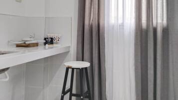 A bathroom with a white sink, a mirror, a towel rack, and a stool.