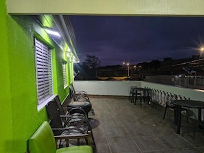 An outdoor patio area with seating and a view of the cityscape at dusk. - Pousada do Sossego Mar e Verde 1 (Itanhaem)