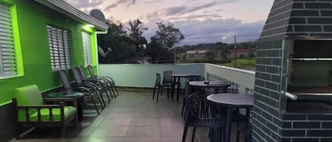 A rooftop terrace with outdoor seating, a brick oven, and a green wall.