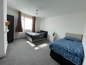 A bedroom with a bed, a dresser, a radiator, and a window with curtains. - 1 Bedroom Apartm Sleeps 3 Driveway Near Leagrave T (Luton)