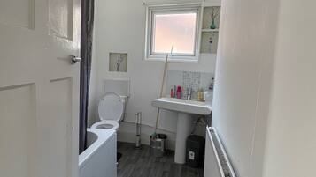 Un baño pequeño con inodoro, lavamanos y zona de ducha.