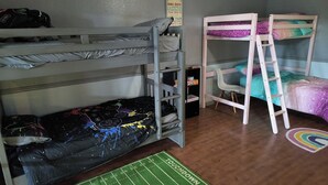 Habitación con literas, alfombra con motivos de fútbol y una alfombra de arcoíris en el suelo.