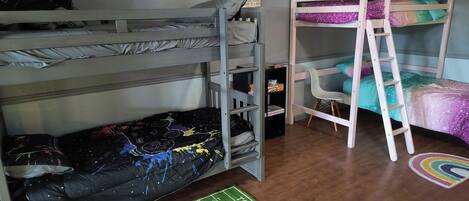 Habitación con literas, alfombra con motivos de fútbol y una alfombra de arcoíris en el suelo.