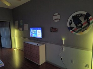 Ein Zimmer mit einem Flachbildfernseher an der Wand, einem Schminktisch und einer Wandlampe.