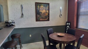 Un comedor con una mesa redonda, cuatro sillas, un cuadro en la pared y una ventana con persianas.