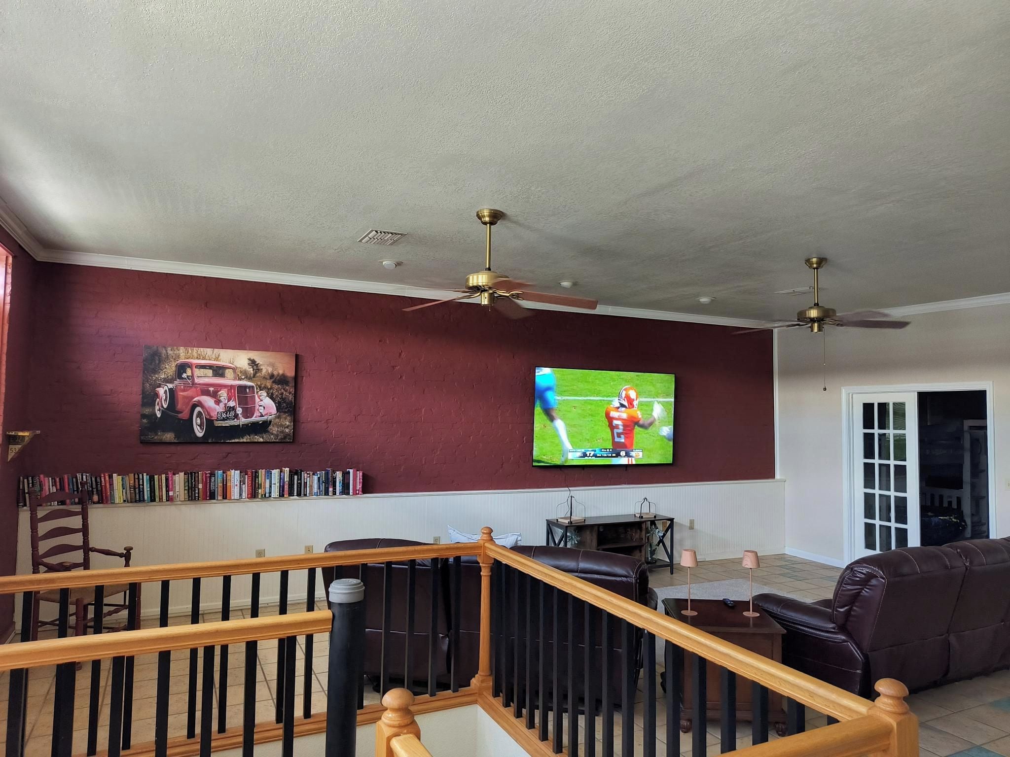 Una sala de estar con televisor, estanterías, chimenea y una escalera.