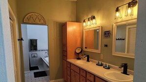 Un baño con dos lavamanos, armarios de madera, un espejo y un cartel que dice 'WASH YOUR HANDS'.
