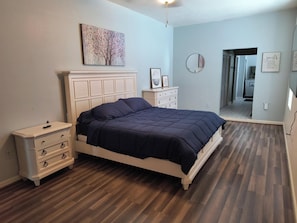 A bedroom with a bed, dresser, and artwork on the wall.