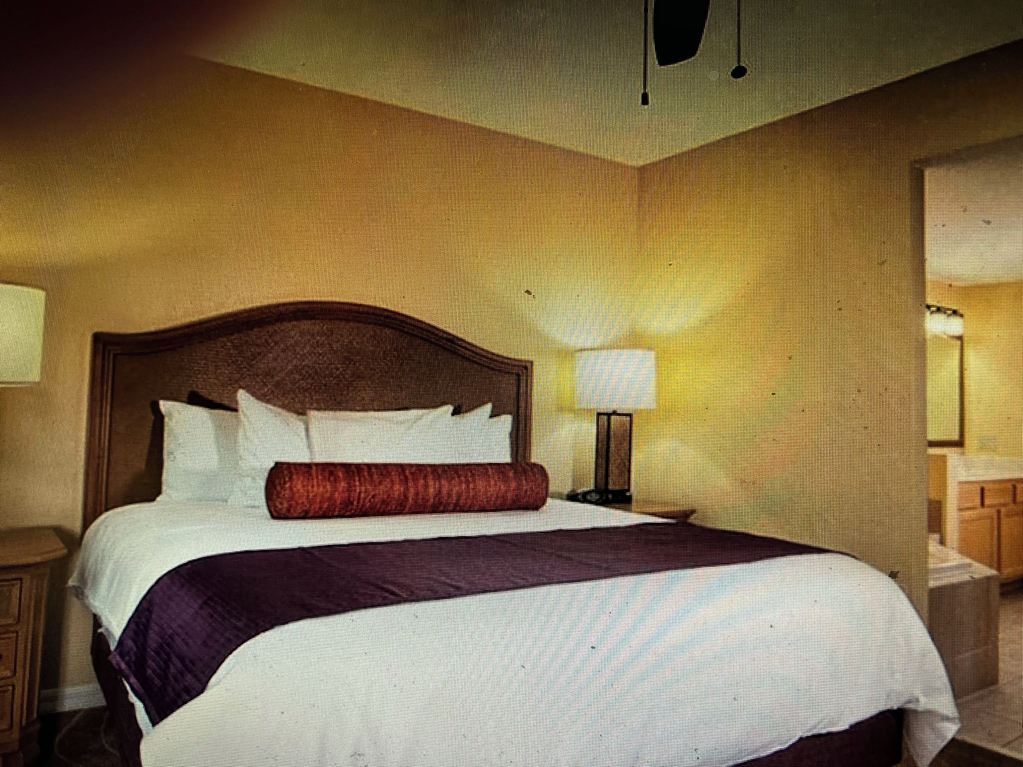 Een hotelkamer met een groot bed, een nachtkastje en een wandlamp.